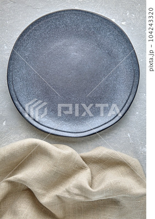 an empty blue ceramic plate and a beige rough linen napkin on a an empty blue ceramic plate and a beige rough linen napkin on a 104243320
