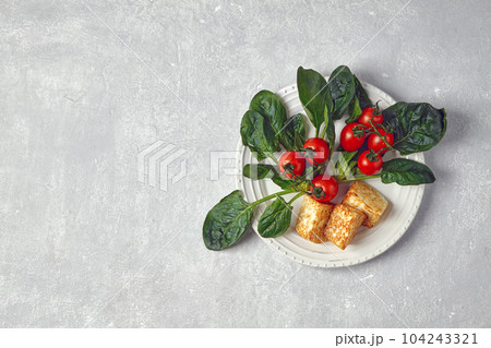 Red cherry tomatoes on a branch, green spinach leaves and fried Red cherry tomatoes on a branch, green spinach leaves and fried 104243321