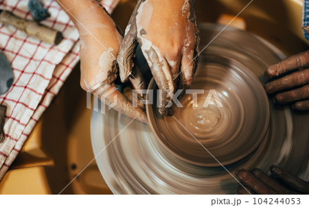Craftsman potter making jug of clay on the potter's wheel circle in workshop Craftsman potter making jug of clay on the potter's wheel circle in workshop 104244053