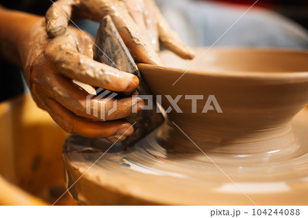Close up on skillful hands sculpting pottery jar on potter wheel 104244088