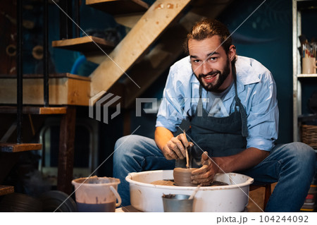 Craftsman potter making jug of clay on the potter's wheel circle in workshop Craftsman potter making jug of clay on the potter's wheel circle in workshop 104244092