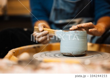 Close up on skillful hands sculpting pottery jar on potter wheel Close up on skillful hands sculpting pottery jar on potter wheel 104244153