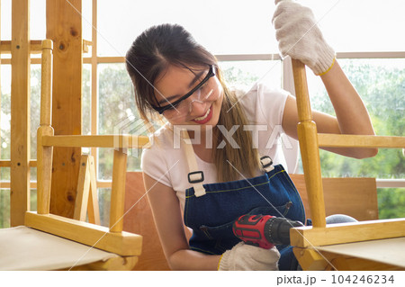 Portrait of professional female carpenter worker using electrical screwdriver 104246234
