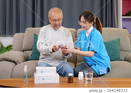 Caregiver nurse taking care of elderly grandfather sitting on sofa at home 104246372