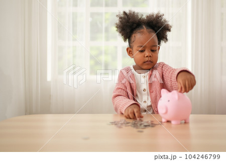 Little girl putting coin of cash into ceramic piggy bank Little girl putting coin of cash into ceramic piggy bank 104246799
