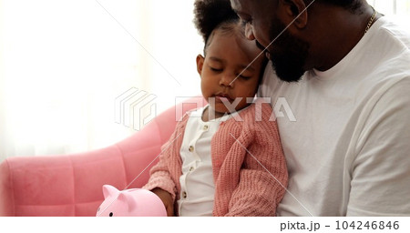 Daughter and father saving money putting coin of cash into ceramic piggy bank Daughter and father saving money putting coin of cash into ceramic piggy bank 104246846