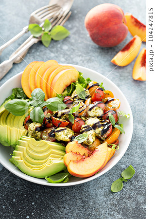 Avocado peach caprese salad with basil pesto 104247815