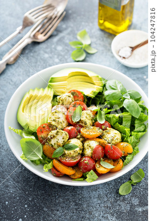 Avocado caprese salad with basil pesto 104247816