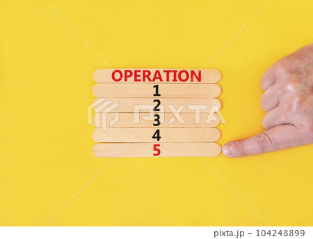 Time to operation 5 symbol. Concept word Operation 1 2 3 4 5 on wooden sticks. Businessman hand. Beautiful yellow table yellow background. Business planning and time to operation 5 concept. Copy space Time to operation 5 symbol. Concept word Operation 1 2 3 4 5 on wooden sticks. Businessman hand. Beautiful yellow table yellow background. Business planning and time to operation 5 concept. Copy space 104248899