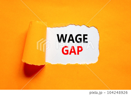 Wage gap symbol. Concept words Wage gap on beautiful white paper on a beautiful orange background. Business, support and wage gap concept. Copy space. Wage gap symbol. Concept words Wage gap on beautiful white paper on a beautiful orange background. Business, support and wage gap concept. Copy space. 104248926