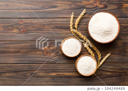 Flat lay of Wheat flour in wooden bowl with wheat spikelets on colored background. world wheat crisis 104249489