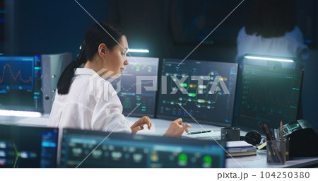 Female IT technical specialist works on computer with data server Female IT technical specialist works on computer with data server 104250380
