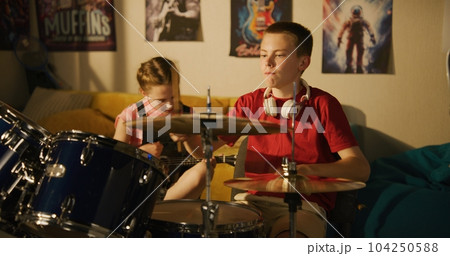 Young boy and girl play drum kit and ukulele in bedroom 104250588