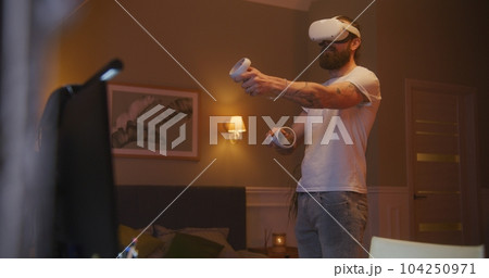 Man plays game using VR headset and controllers Man plays game using VR headset and controllers 104250971