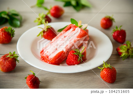 homemade strawberry ice cream on a stick in a plate with strawberries homemade strawberry ice cream on a stick in a plate with strawberries 104251605