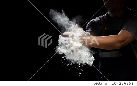 Chef prepare white flour dust for cooking bakery food. Elderly man Chef clap hand, white flour dust explode fly in air. Flour stop motion in air with freeze high speed shutter, black background Chef prepare white flour dust for cooking bakery food. Elderly man Chef clap hand, white flour dust explode fly in air. Flour stop motion in air with freeze high speed shutter, black background 104256852