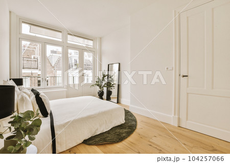 a bedroom with white walls and wood flooring the room is well lit by the sun shining through the windows a bedroom with white walls and wood flooring the room is well lit by the sun shining through the windows 104257066