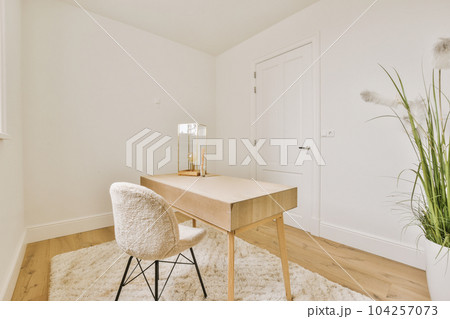 a desk and chair in the corner of a room with white walls, wood flooring and a plant next to it a desk and chair in the corner of a room with white walls, wood flooring and a plant next to it 104257073