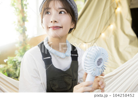 家キャンでネッククーラーと携帯扇風機で涼む若い女性 キャンプイメージ 家キャンでネッククーラーと携帯扇風機で涼む若い女性 キャンプイメージ 104258452