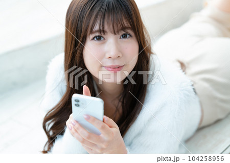 寝転んでスマホを使う若い女性 寝転んでスマホを使う若い女性 104258956