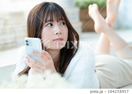 寝転んでスマホを使う若い女性 寝転んでスマホを使う若い女性 104258957