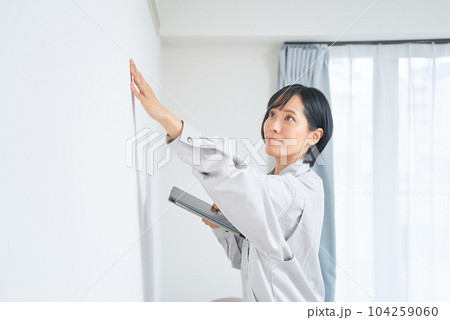 住宅の壁の状態を調べる作業着姿の女性 住宅の壁の状態を調べる作業着姿の女性 104259060