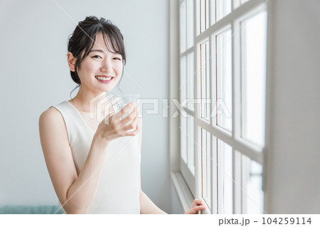 家で水・ミネラルウォーター・白湯をコップで飲むリラックスした女性 104259114