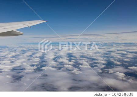 Airplane window captivated by stunning view of Earth majestic landscapes vastness of cloudy sky. 104259639