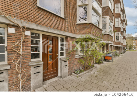 an urban street with brick buildings in the background and trees on either side of the street, there is a bicycle parked next to an urban street with brick buildings in the background and trees on either side of the street, there is a bicycle parked next to 104266416