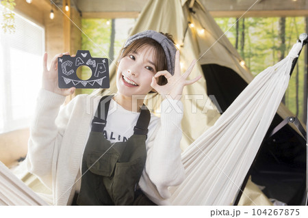 ハンモックに座って文字を見せる若い女性　　家キャン おうちキャンプ　キャンプイメージ 104267875