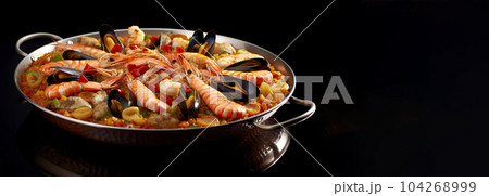 Large skillet with delicious paella on dark background, restaurant concept, healthy food Large skillet with delicious paella on dark background, restaurant concept, healthy food 104268999