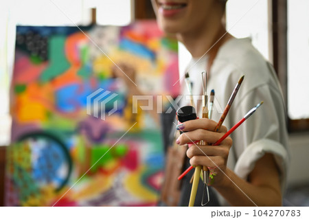 Select focus on hand of artist holding paintbrushes standing in art studio. Art, hobby and leisure activity concept 104270783