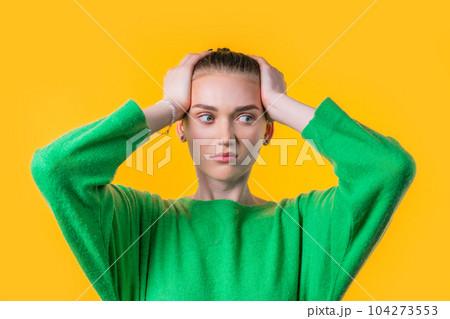 Woman afraid of something, she in shock on yellow backdrop.Holding head 104273553