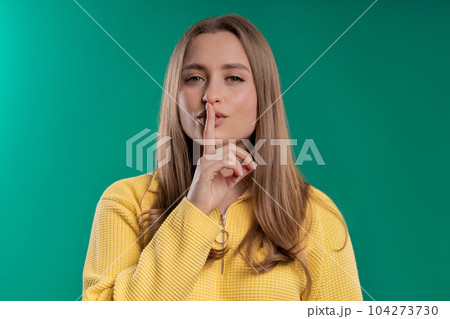 Smiling pretty woman with finger on lips - shhh, secret, silence, blue studio Smiling pretty woman with finger on lips - shhh, secret, silence, blue studio 104273730