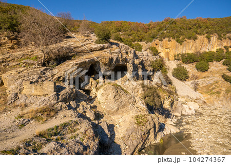 High canyons with green vegetation along the Osumi river in Albania. A narrow valley and a little bridge connecting the canyons. 104274367