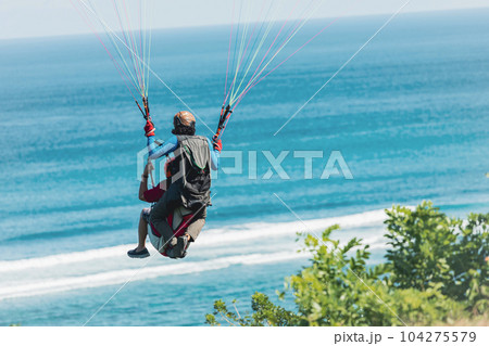 Paraglider flies in front of the ocean Paraglider flies in front of the ocean 104275579