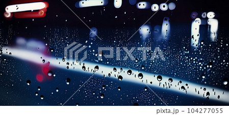 Rain shower on car windshield or car window and blurry road in background. Driving in rainy season. Rain drops on car mirror. Traffic road in evening rain. Drizzle raining decreases driving visibility 104277055