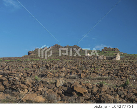 Abandoned ruins of farm house at flat plateau on top of La Merica mountain with cacti, stones and sea view. valle Gran Rey, La Gomera, Canary Islands. Copy space. 104277751
