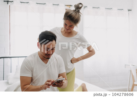 Funny couple. Wife peeking husband who chatting on the smartphone. Funny couple. Wife peeking husband who chatting on the smartphone. 104278606