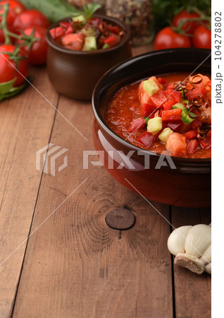 Traditional spanish cold gazpacho tomato soup on wood background with place for text. Ingredients around the cooked soup. Recipe, menu. Vegetarian healthy food. Traditional spanish cold gazpacho tomato soup on wood background with place for text. Ingredients around the cooked soup. Recipe, menu. Vegetarian healthy food. 104278802