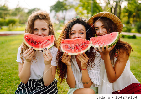 Cheerful happy friends camping on the grass, eating watermelon, laughing. 104279134