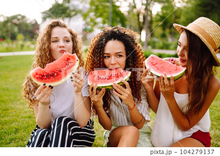 Three young woman have fun together and eating watermelon in hot summer day. Three young woman have fun together and eating watermelon in hot summer day. 104279137