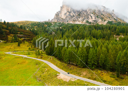 Road near the forest in the foot of the mountains covered with clouds. Road near the forest in the foot of the mountains covered with clouds. 104280901