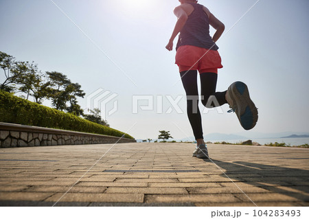 young asian adult woman running jogging outdoors, rear and low angle view 104283493