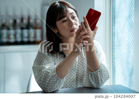 スマホを見てショックを受けるミドル女性 104284007