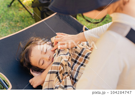 キャンプ場に来て遊び疲れてコットに眠る子供（体調不良・発熱） 104284747