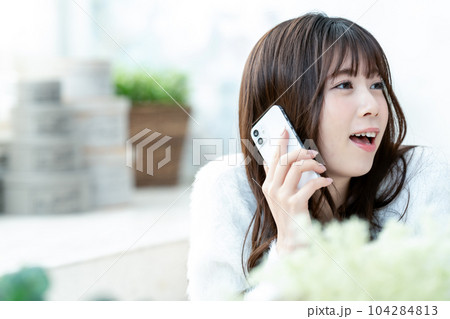 寝転んでスマホ通話する若い女性 104284813