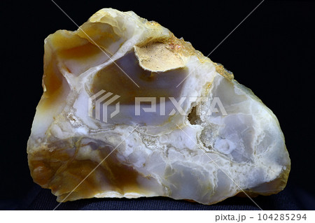 A polished plate of bluish chalcedony against a dark background 104285294