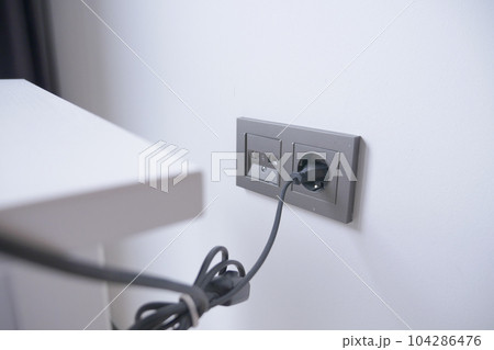 white color power cord cable plugged into wall white color power cord cable plugged into wall 104286476