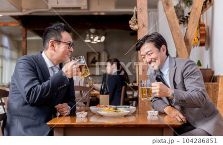 居酒屋で酒・ビールを飲みながら同僚・友達と楽しく会話するビジネスマン 104286851